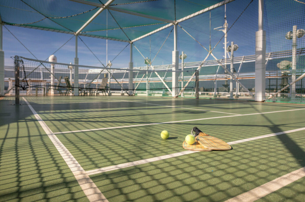 Tennisplatz auf dem Außendeck der Queen Victoria mit grünem Belag, Netz und Schlägern