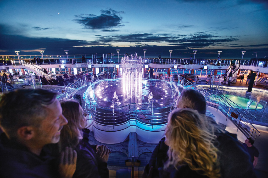 Der Fountain Pool mit illuminiertem Wasserspiel bei Abenddämmerung auf der Royal Princess.