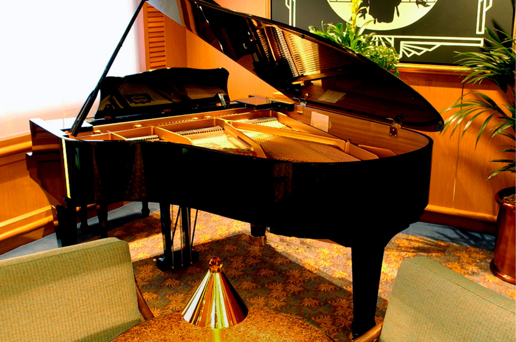 Crooners Bar mit schwarzem Konzertflügel, gepolsterten Sesseln und warmer Pianobar-Atmosphäre.