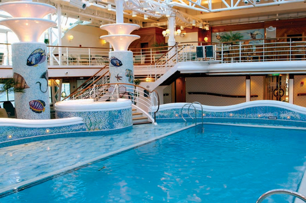 Innenpool Calypso Pool mit Mosaiksäulen, Fischmotiven und Glasdach an Bord des Kreuzfahrtschiffs.