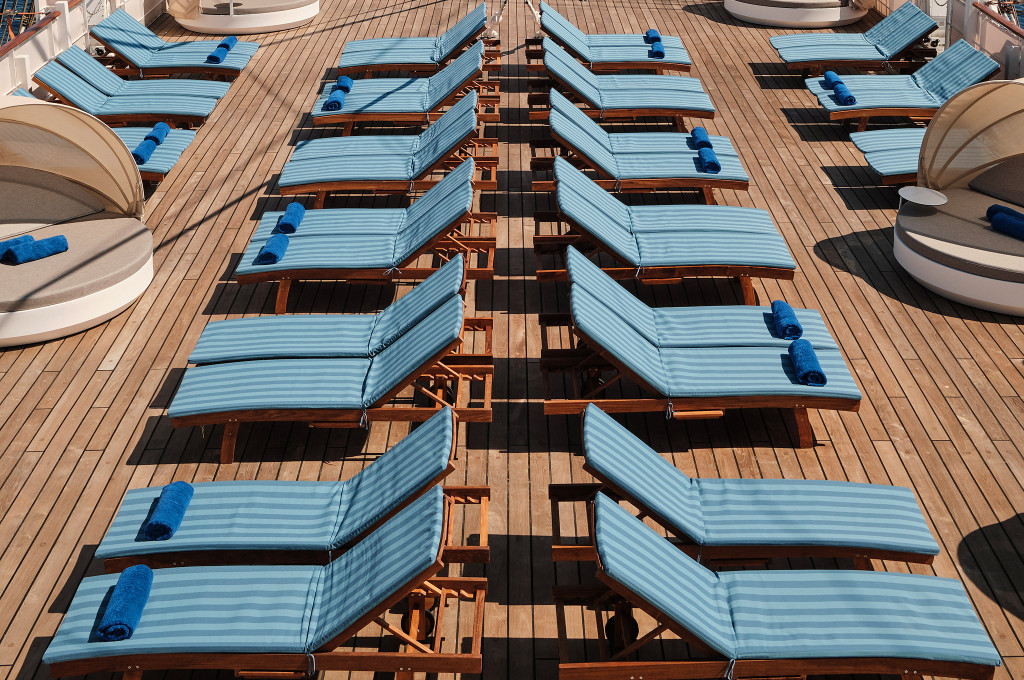 Sonnendeck der Sea Cloud Spirit mit Reihen blau gestreifter Liegestühle und runden Liegeinseln auf dem Teakdeck.