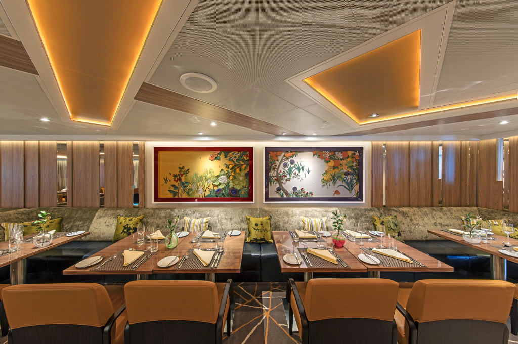 The Colonnade auf der Seabourn Ovation mit gedeckten Tischen, bunten Wandgemälden und warmem Ambiente.