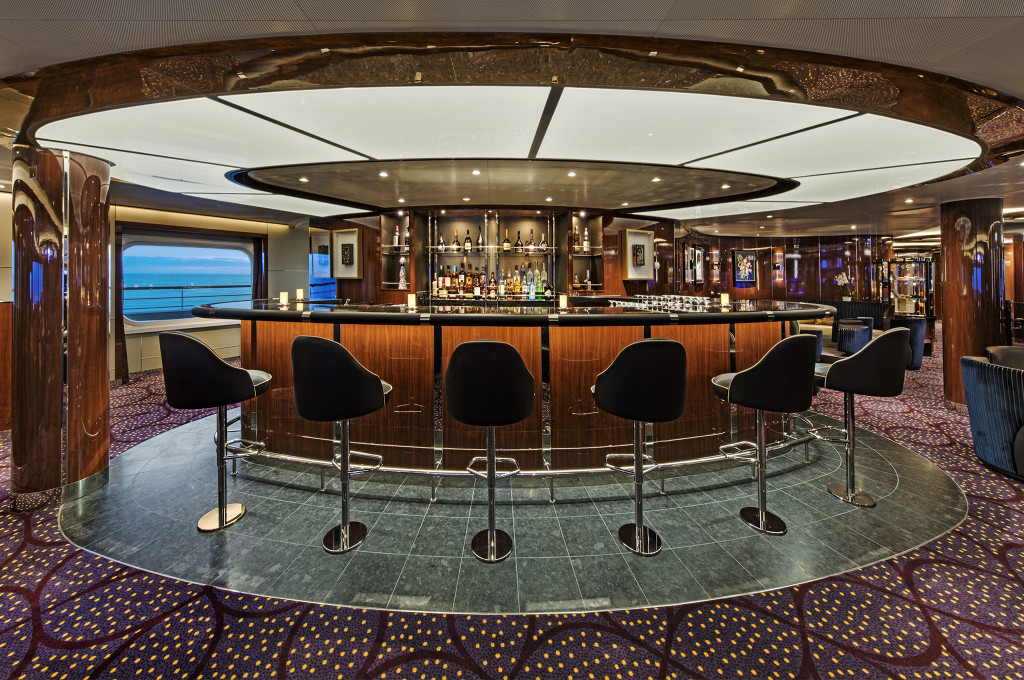 The Club auf der Seabourn Ovation mit runder Bartheke, schwarzen Barhockern und eleganter Beleuchtung.
