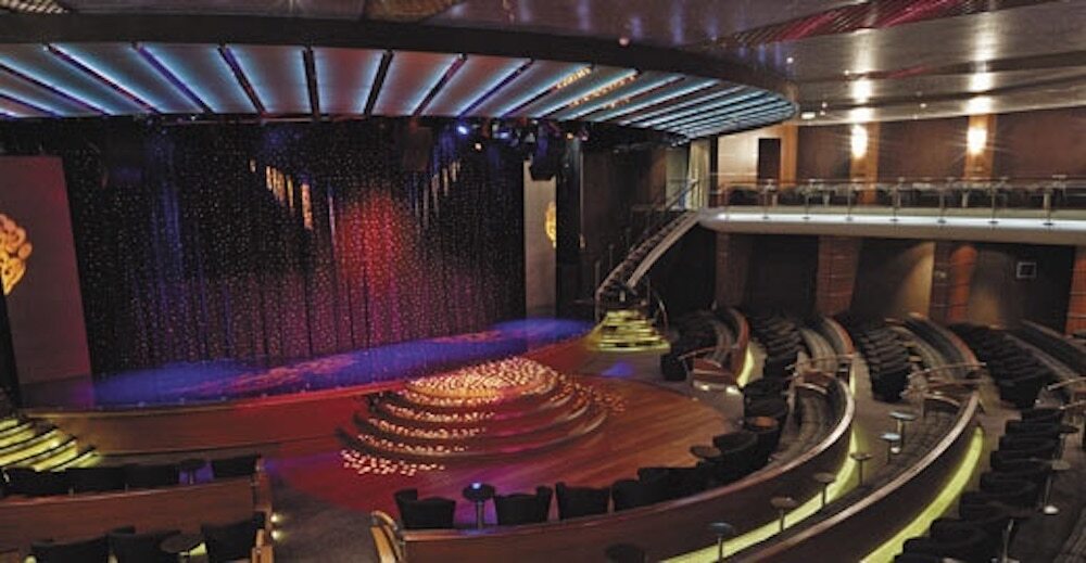 Mehrstöckiges Constellation Theater mit Bühnenvorhang, Balkonrang und warmer Ambientebeleuchtung auf der Seven Seas Mariner
