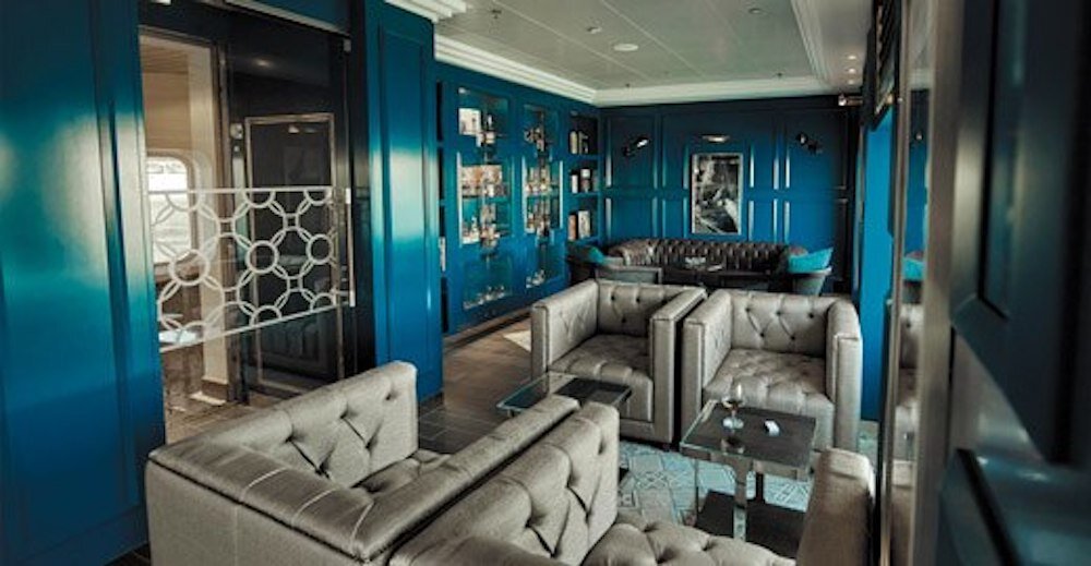 Exklusive Club-Lounge mit Chesterfield-Sofas, türkisfarbenen Wänden und Glasvitrinen auf der Seven Seas Mariner