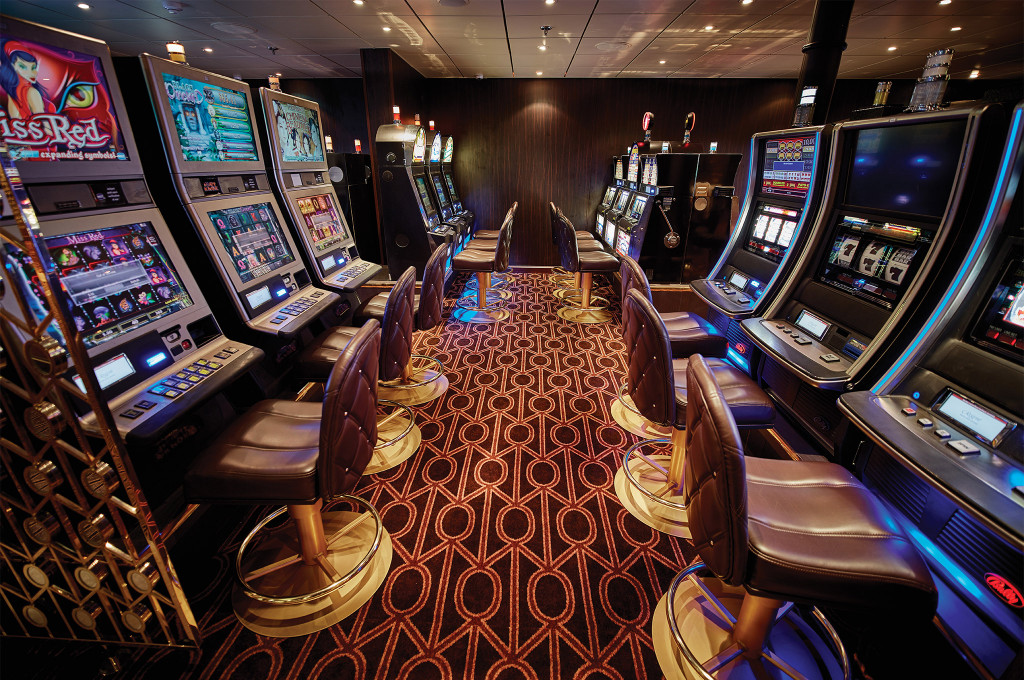 Casino-Bereich mit beleuchteten Spielautomaten und Lederhockern an Bord der Seven Seas Navigator.