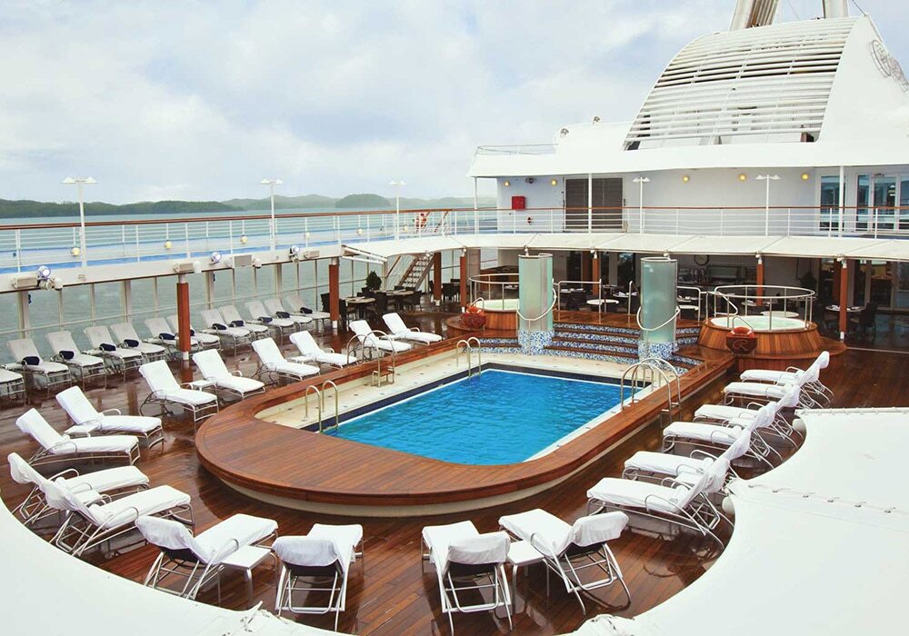 Pool mit Liegestühlen, Sonnenschirmen und Meerblick auf Hochsee-Kreuzfahrtschiff