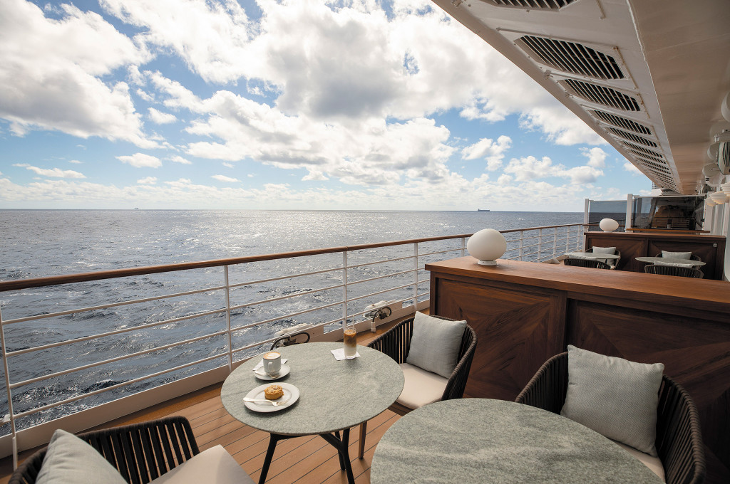 Außenterrasse der Coffee Connection mit Sitzgruppen, Cappuccino-Tasse und freiem Meerblick an Bord der Seven Seas Splendor.