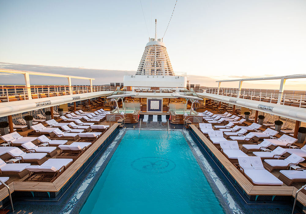 Pool mit Liegestühlen, Meerblick und Schiffsoberteil auf Hochsee-Kreuzfahrtschiff