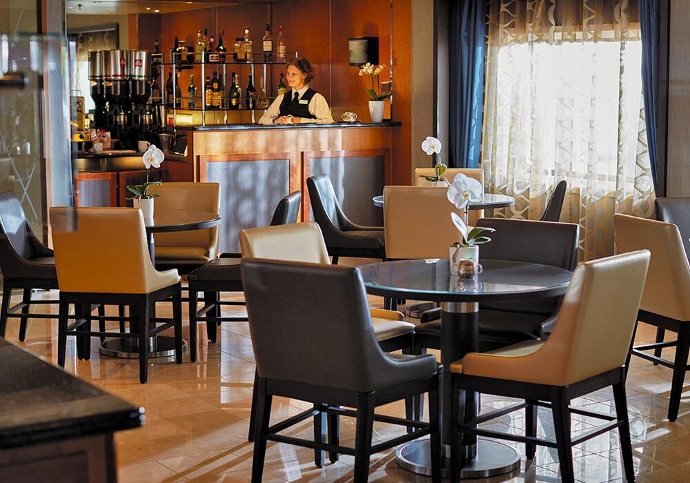Coffee Connection mit Bartresen und Sitzbereichen auf Luxuskreuzfahrtschiff