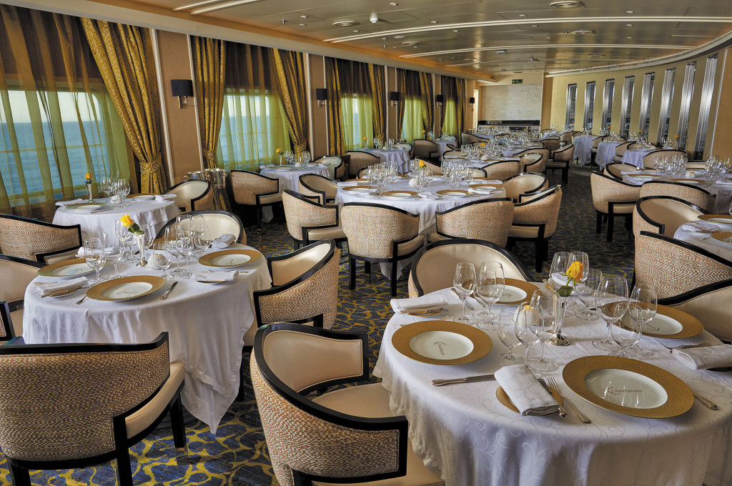 Hauptrestaurant Chartreuse mit eingedeckten Tischen, Korbsesseln und Panoramafenstern zum Meer.