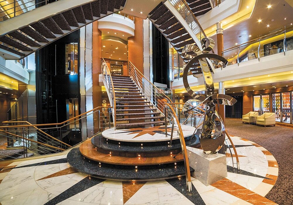 Atrium mit Treppe, Lounge und eleganter Dekoration auf Luxuskreuzfahrtschiff
