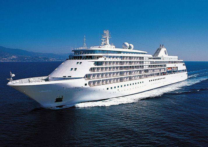 Elegantes Kreuzfahrtschiff in voller Fahrt vor einer Küstenlandschaft