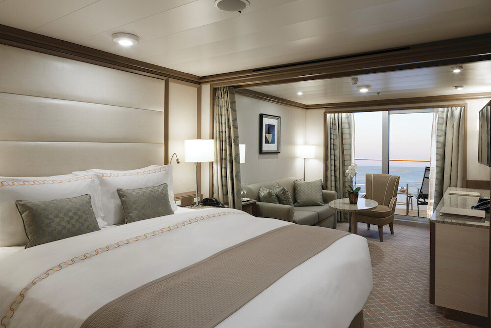 Luxuriöse Veranda-Suite auf der Silver Spirit mit Doppelbett, Sitzecke und Balkon mit Meeresblick bei Sonnenuntergang