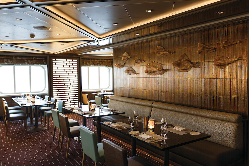 Asiatisches Spezialitätenrestaurant Indochine mit Holzreliefwand, Banquettesitzen und dunklen Tischen