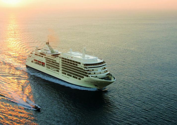 Kreuzfahrtschiff aus der Vogelperspektive bei Sonnenuntergang mit einem Beiboot in der Nähe