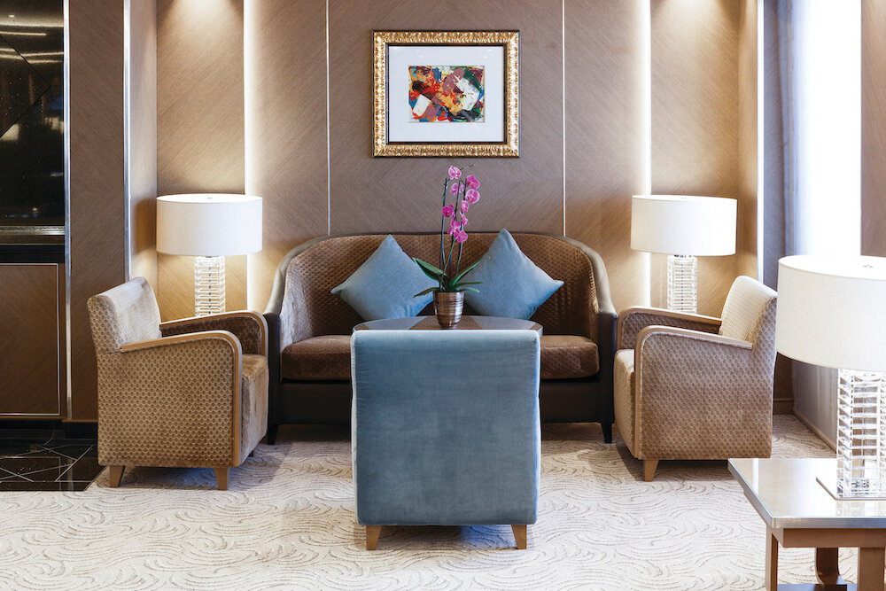 Eleganter Lounge-Sitzbereich mit gemusterten Sesseln, Orchidee, Tischlampen und modernem Kunstwerk auf der Silver Spirit