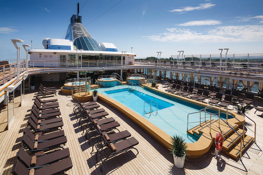 Elegantes Pooldeck der Silver Spirit mit rechteckigem Pool, Liegestühlen, Whirlpools und dekorierten Palmen