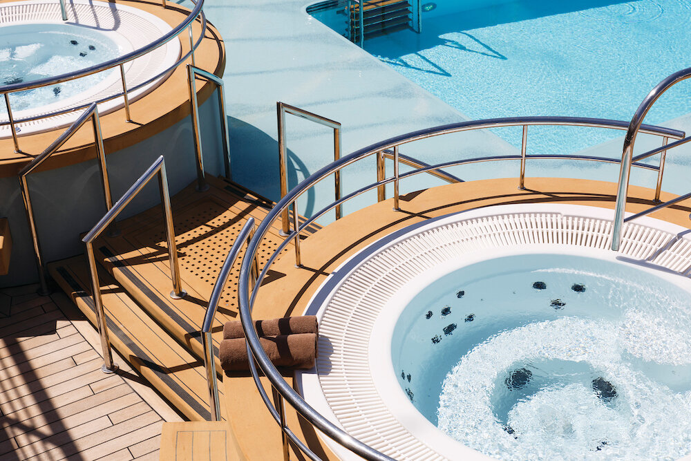 Zwei runde Außen-Whirlpools auf dem Pooldeck der Silver Spirit mit cremefarbenem Deckbelag und angrenzend Pool