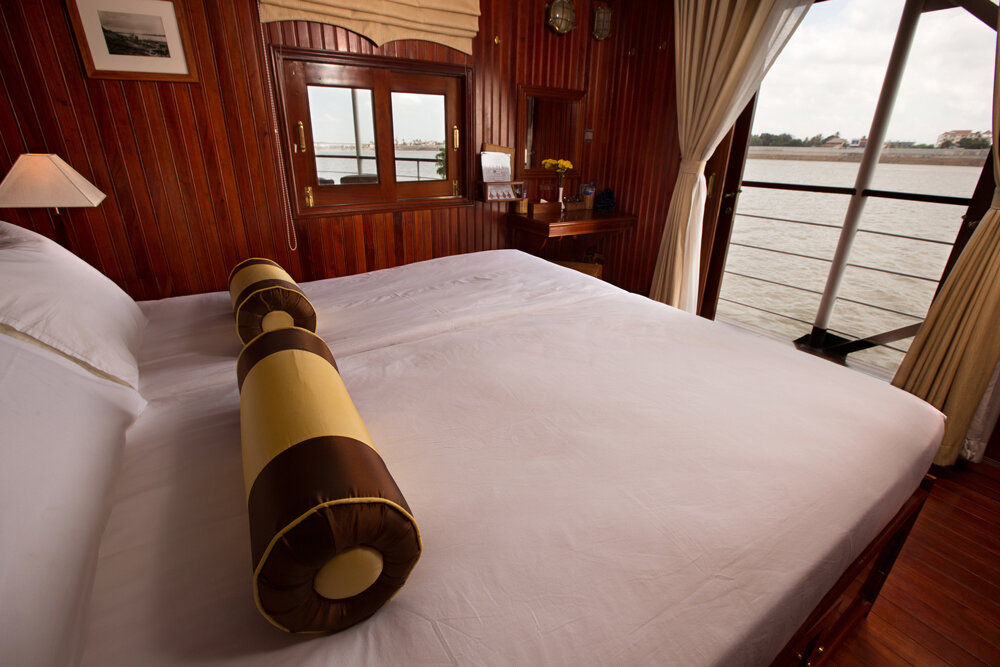 Kabine auf dem Oberdeck mit Doppelbett, Holzvertäfelung, Schreibtisch und offener Tür mit Blick auf den Fluss