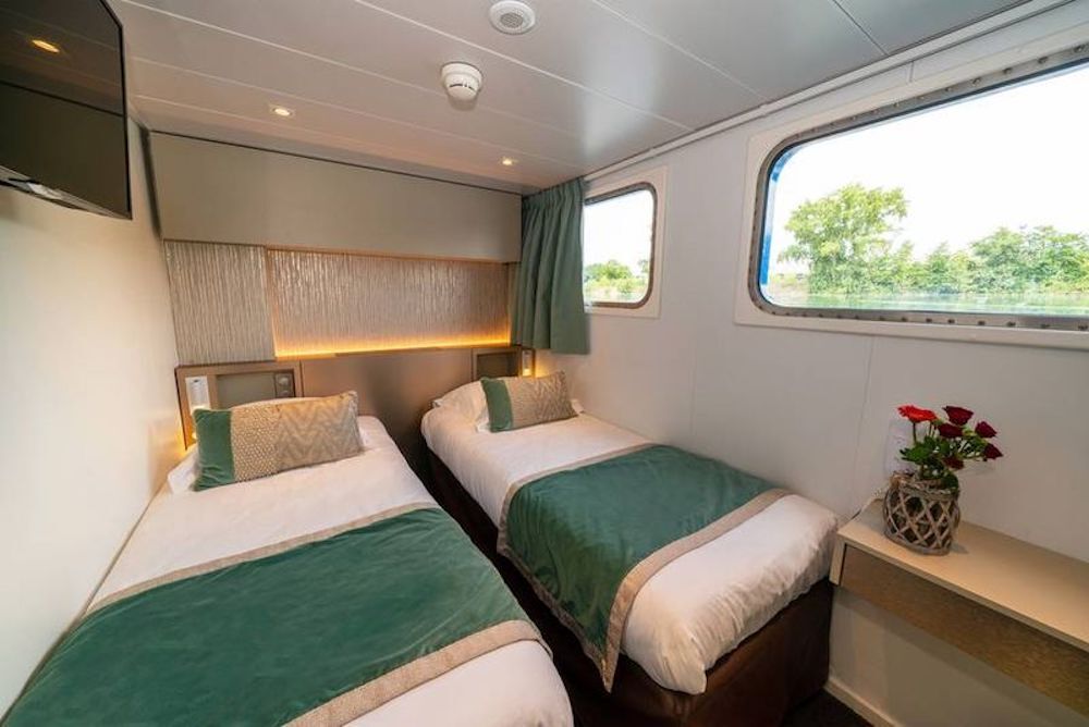 Zweibettkabine auf dem Hauptdeck einer Péniche mit zwei Einzelbetten und Fenstern auf Wasserhöhe.
