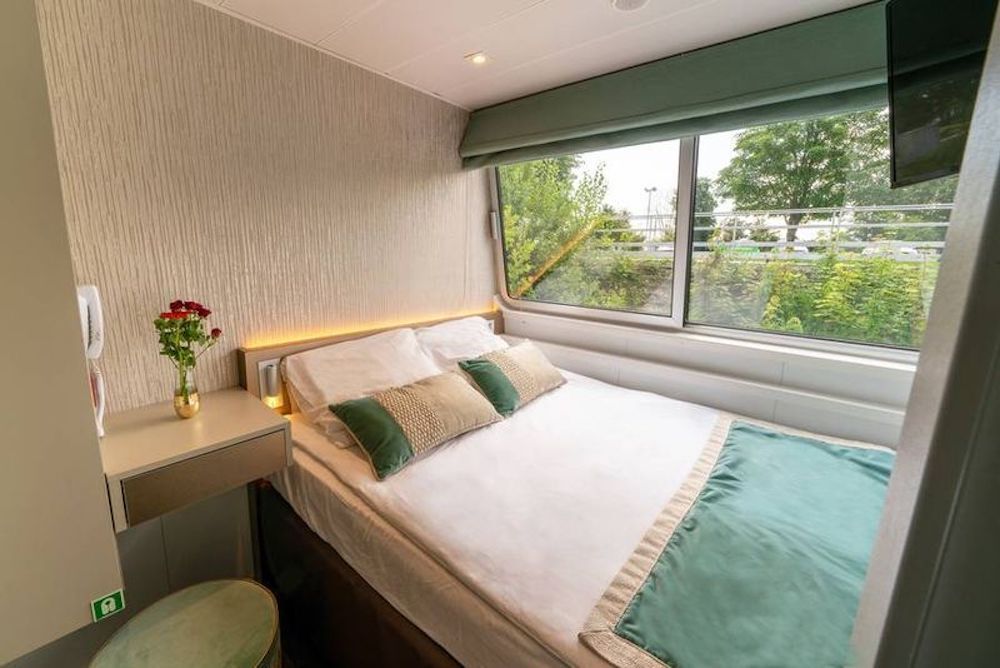 Zweibettkabine auf dem Oberdeck einer Péniche mit französischem Doppelbett direkt am breiten Panoramafenster.