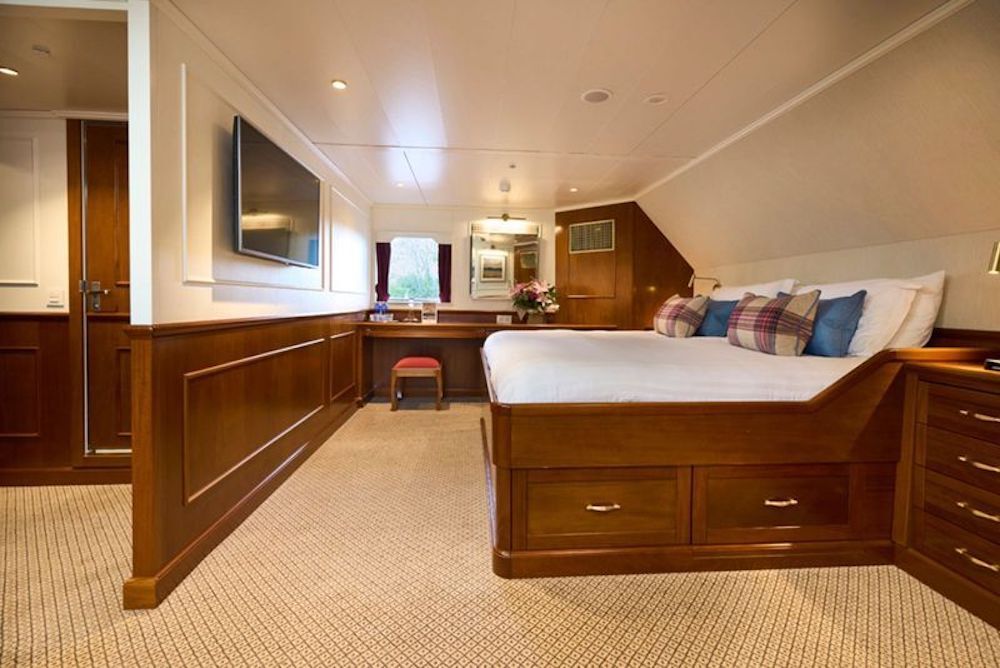 Geräumige Suite mit breitem Doppelbett, durchgehendem Schreibtisch, Mahagoni-Vertäfelung und Panoramafenster.