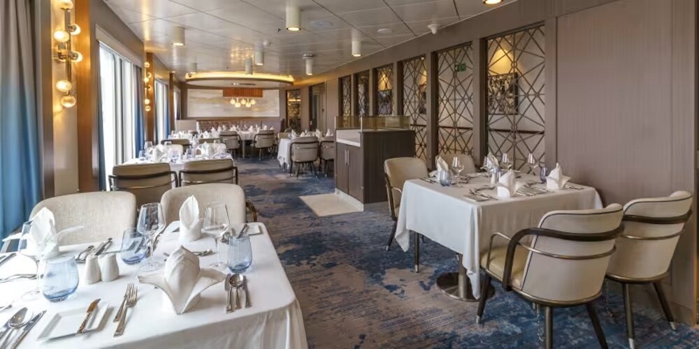 Privates Restaurantzimmer mit gedeckten Tischen, weißen Tischdecken und dekorativen Wandpaneelen