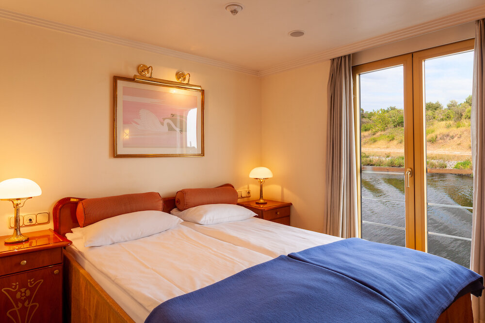 Doppelkabine auf dem Oberdeck mit zusammengestelltem Bett, Wandbild und französischem Balkon mit Blick auf den Fluss