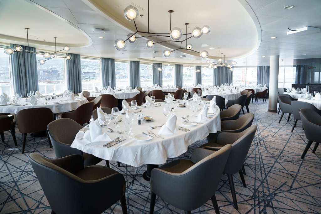 Balena Restaurant der Ultramarine mit gedeckten Rundetischen, modernen Pendelleuchten und Panoramafenstern mit Hafenblick.