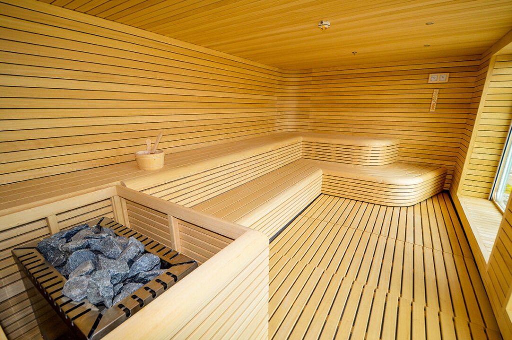 Finnische Sauna auf der Ultramarine mit Holzbänken, Aufgusseimer und Saunaofen mit Steinen.