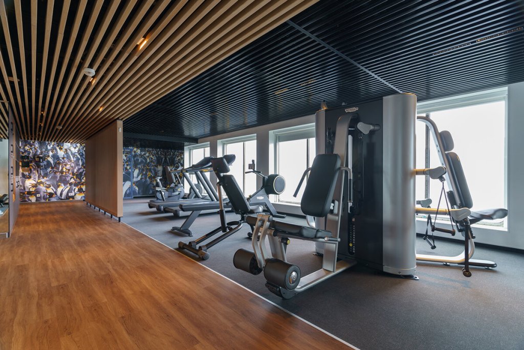 Fitnessraum der Ultramarine mit Laufbändern, Trainingsgeräten und großem Pinguinfoto-Wandbild.