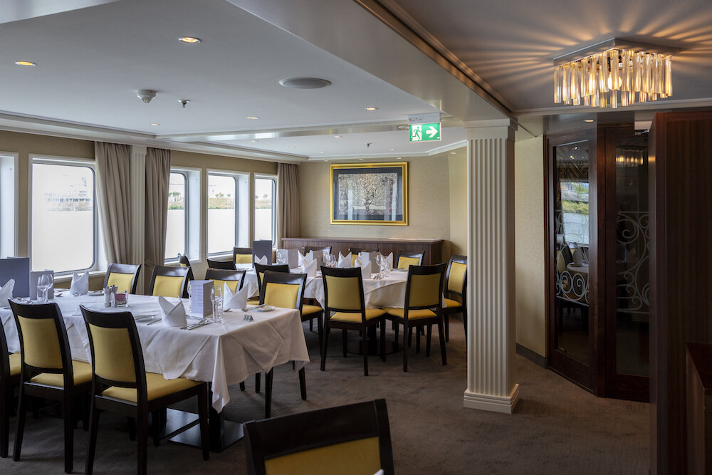 Hauptrestaurant der MS Vistabaroness mit gedeckten Tischen und heller Ausstattung