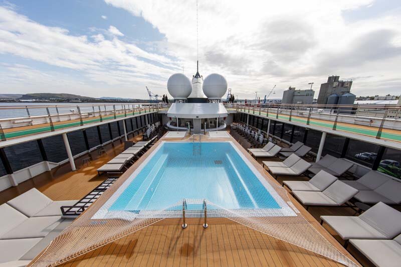 Außenpool auf dem Sonnendeck der World Explorer mit Liegestühlen und charakteristischen Kugelschornsteinen.