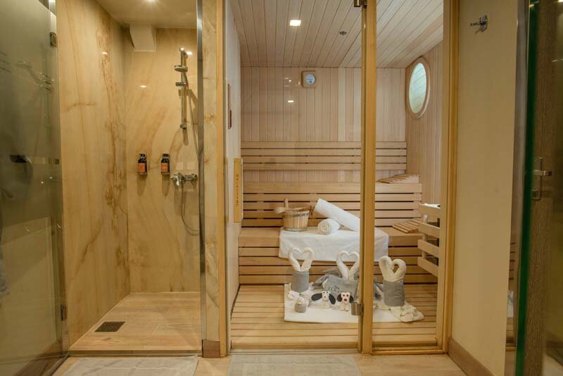 Sauna auf der World Explorer mit Holzbänken, dekorierten Handtuchtieren und angrenzendem Duschbereich.
